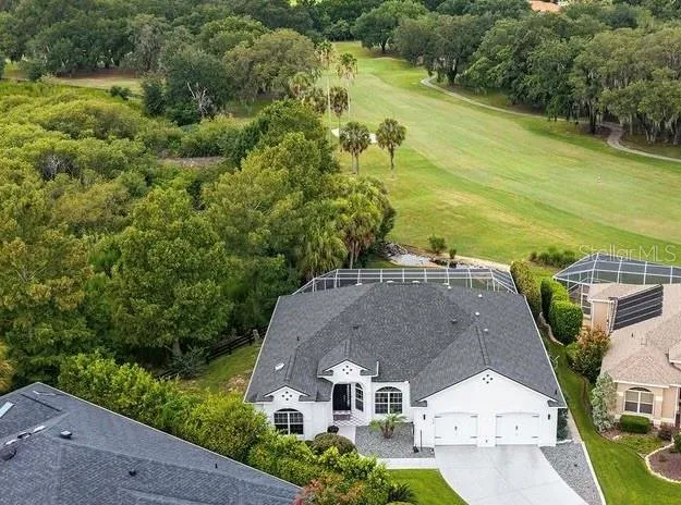 Aerial view showcases the home’s desirable position along the golf course, with mature trees, expansive fairway views, and added privacy behind the property.NO HOUSES OR ROADS IN SIGHT!