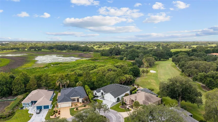 High-altitude aerial view showcases the home’s golf course setting amid mature greenery, nearby waterways, and surrounding residential neighborhoods.