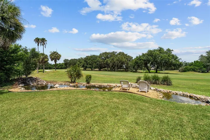 The CUSTOM WATERFALL Koi pond feature in the backyard overlooks beautifully maintained green space and the golf course, creating a peaceful setting with mature landscaping and open views.