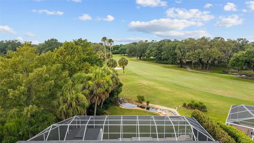 The expansive screen enclosure enjoys a scenic backdrop of manicured fairways, mature trees, and wide-open green space.