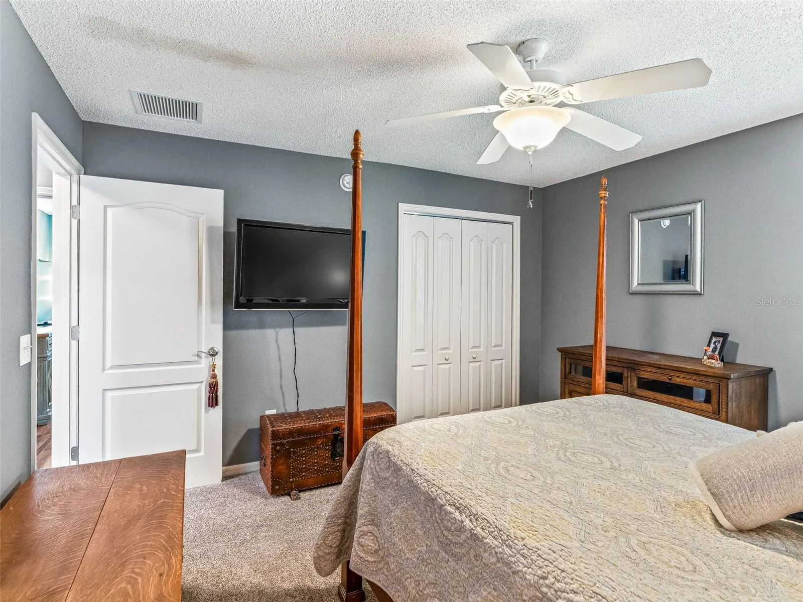 This welcoming bedroom offers a roomy layout, ceiling fan, closet storage, and easy access to the adjoining hallway.