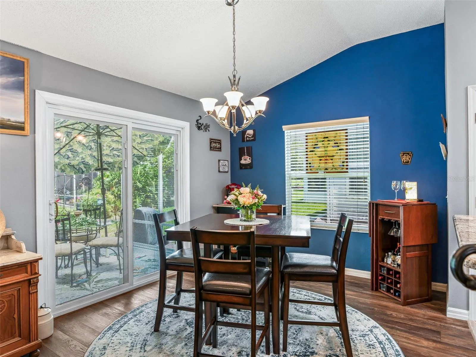 A cheerful dining space features a bold accent wall, chandelier, and UPGRADED sliding glass doors that bring in natural light and provide convenient outdoor access.