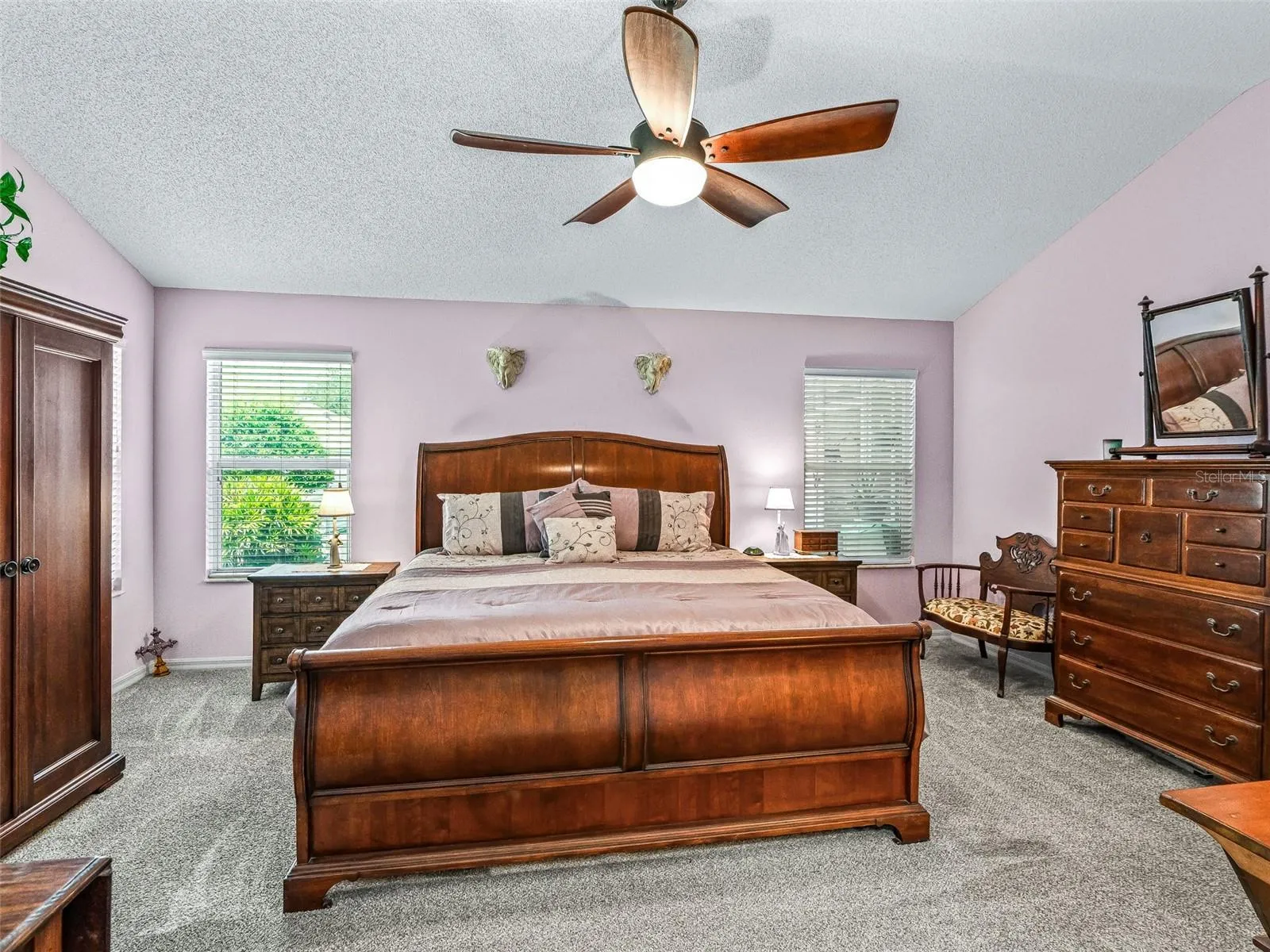 Natural light from multiple windows enhances the comfortable primary bedroom, which offers abundant floor space and a ceiling fan for added comfort.