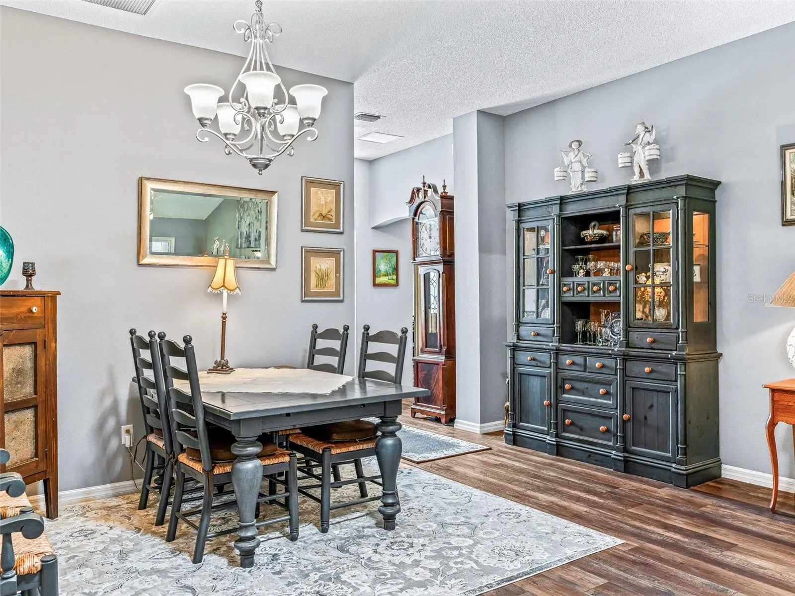 Comfortable dining space features an attractive chandelier, wood-look flooring, and room for a large table, china cabinet, or serving pieces.