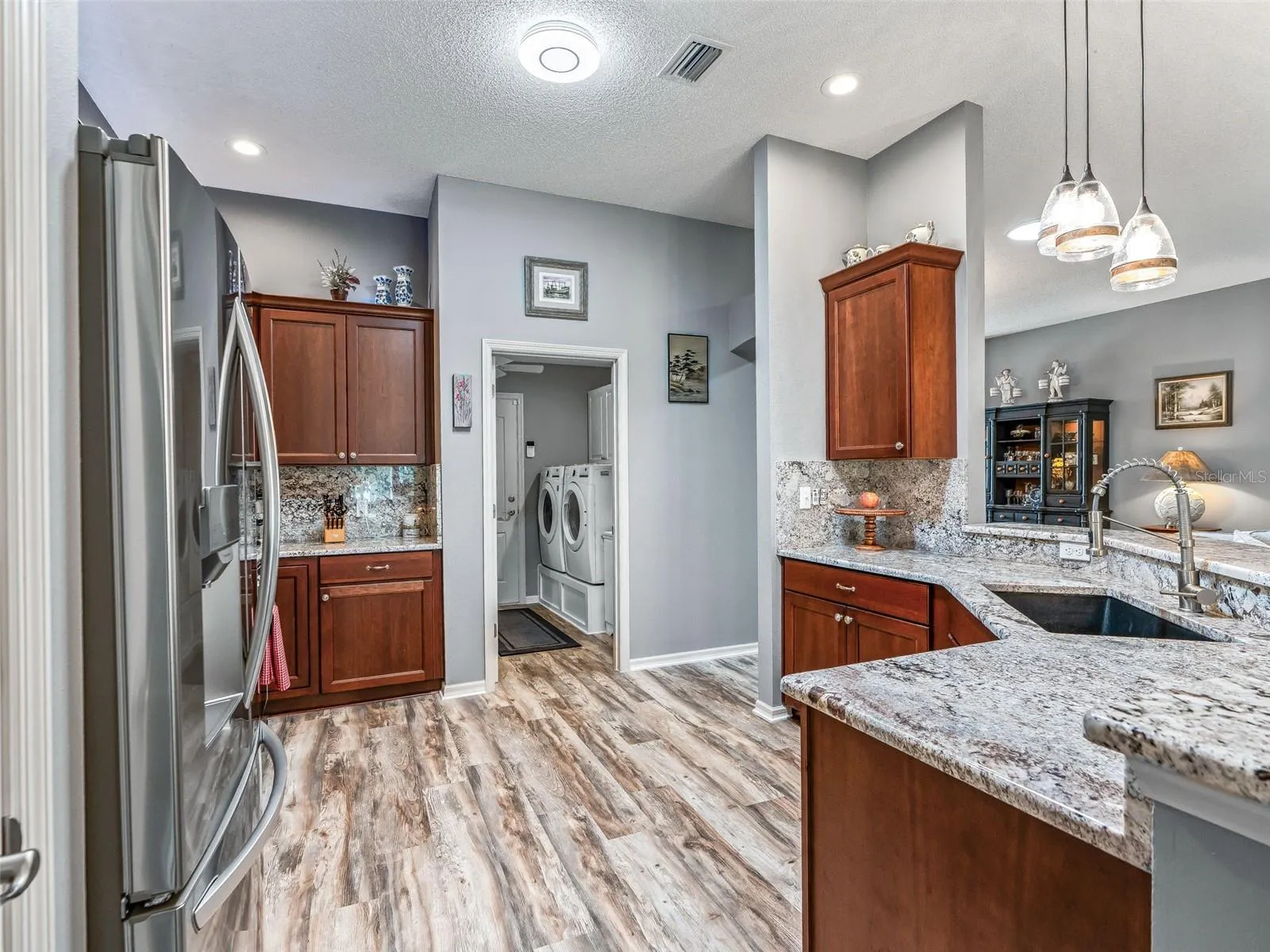 The kitchen offers generous counter space, abundant cabinetry, recessed lighting, and an efficient layout with convenient access to the adjoining utility area.