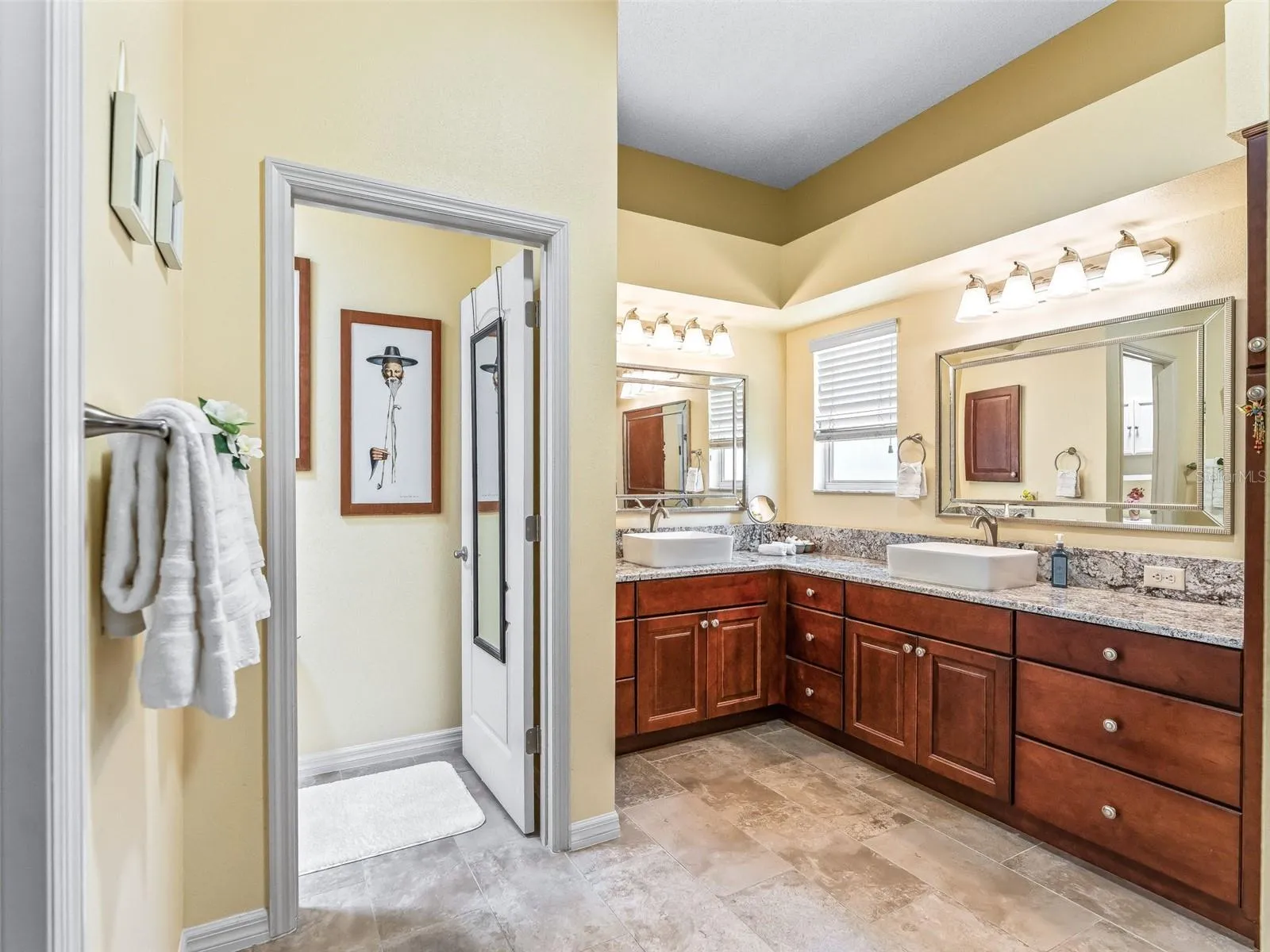 Large primary bath features an extended vanity with abundant cabinetry, generous counter space, dual mirrors, and bright overhead lighting.