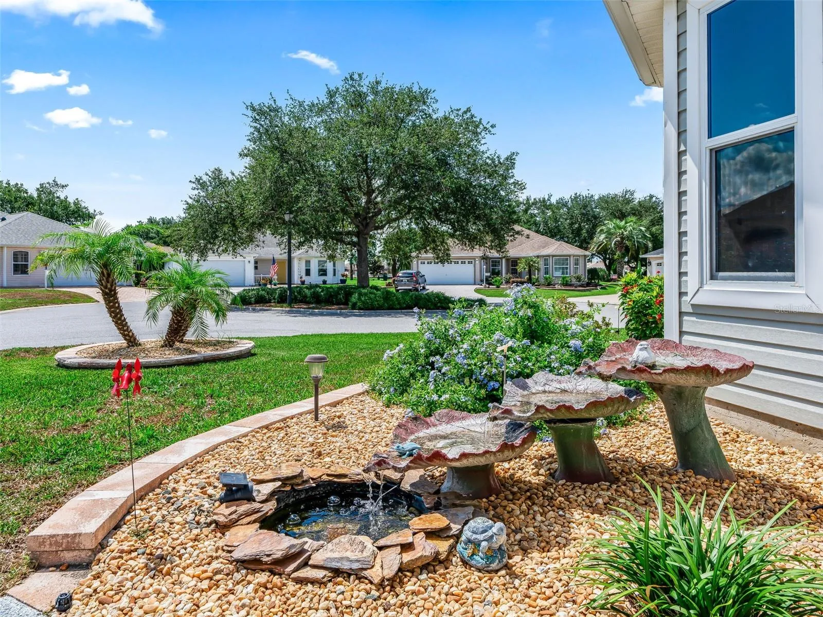 Charming landscaped garden area with mature plantings, decorative stone accents, and a peaceful water feature creates an inviting outdoor focal point.