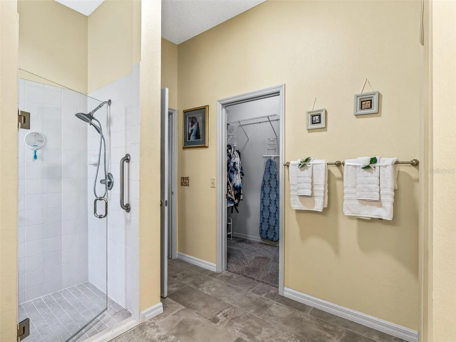 The primary bath includes a walk-in shower with glass enclosure, convenient wall-mounted fixtures, and direct access to the adjoining walk-in closet.