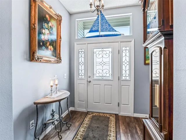 Decorative glass front door with matching sidelights and transom window fills the entry with natural light and creates a polished first impression.