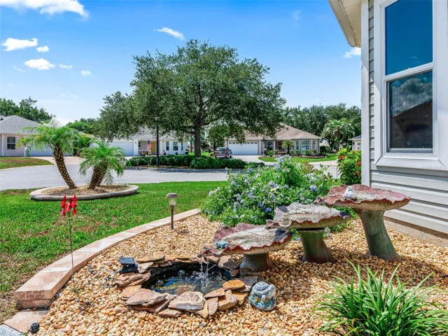 Charming landscaped garden area with mature plantings, decorative stone accents, and a peaceful water feature creates an inviting outdoor focal point.