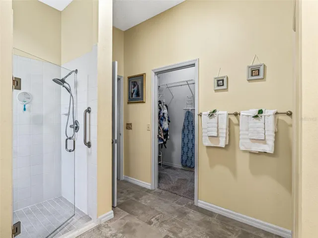 The primary bath includes a walk-in shower with glass enclosure, convenient wall-mounted fixtures, and direct access to the adjoining walk-in closet.