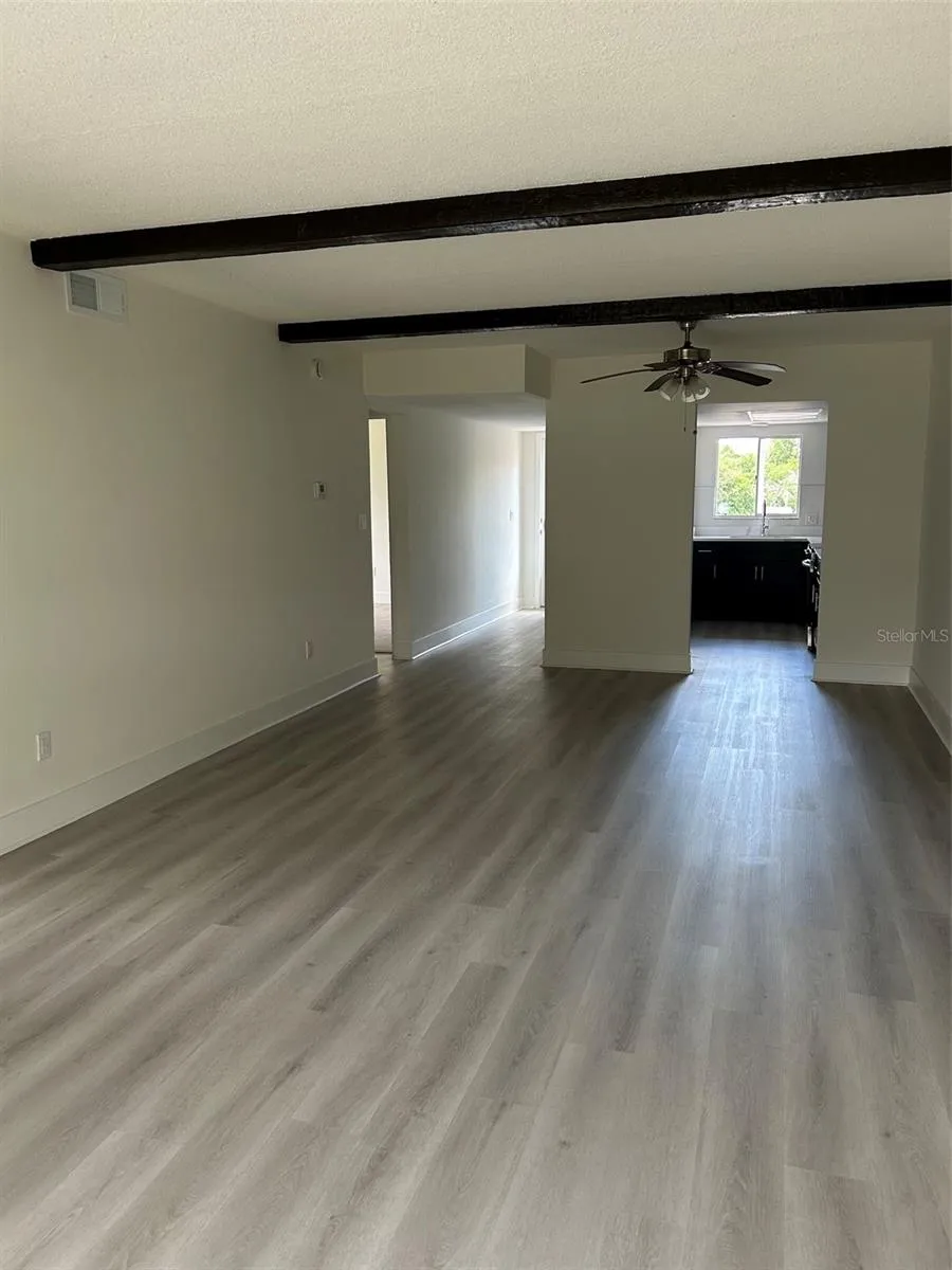 Living room area and dining area and kitchen beyond, viewed from the Florida room. Short hallway seen on the left leads to the front door.