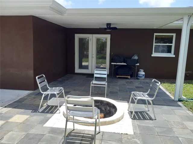 covered patio with slate floor and cement inground fire pit.  French doors open to kitchen which makes it great for entertaining.