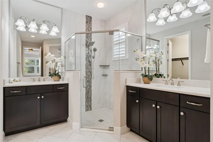 Primary Bathroom w/ a glass enclosed walk-in shower, shower bench seat & separate Quartz countertop vanities