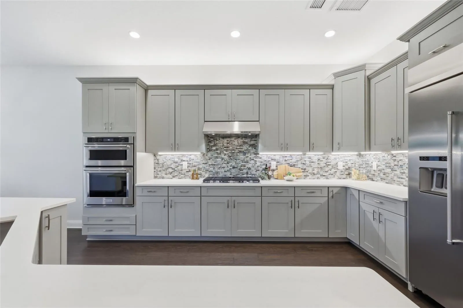 Thoughtfully Designed  Kitchen with Quartz Counter tops, Glass Backsplash, Upgraded Natural Gas Range, Upgraded Cabinets, and Oversized Island