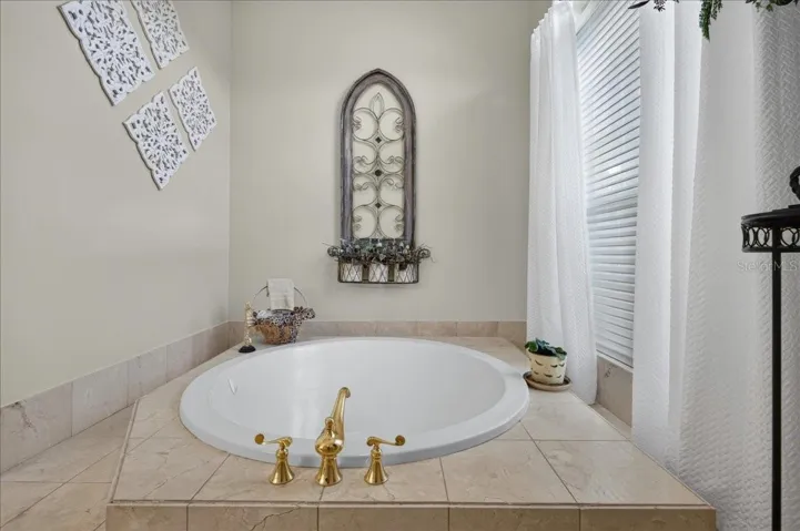 The ensuite bath offers extensive marble finishes, soaking tub, an oversized shower with a curved glass-block wall, double-sink vanity, and a separate water closet with bidet.