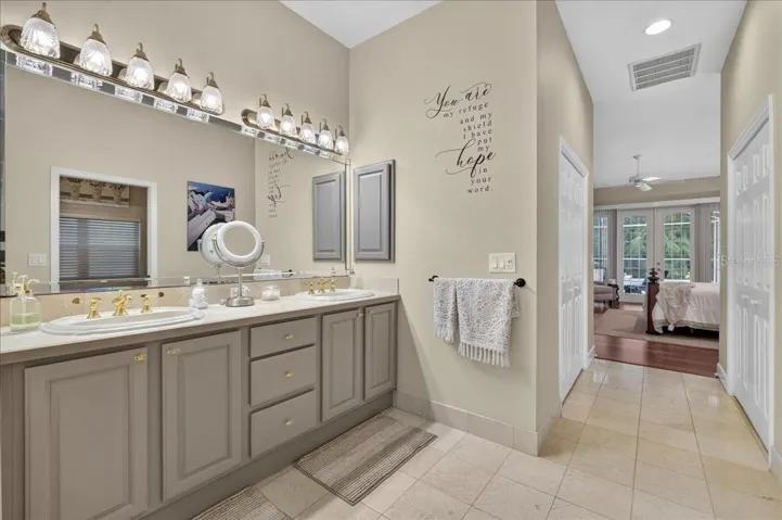 The ensuite bath offers extensive marble finishes, soaking tub, an oversized shower with a curved glass-block wall, double-sink vanity, and a separate water closet with bidet.