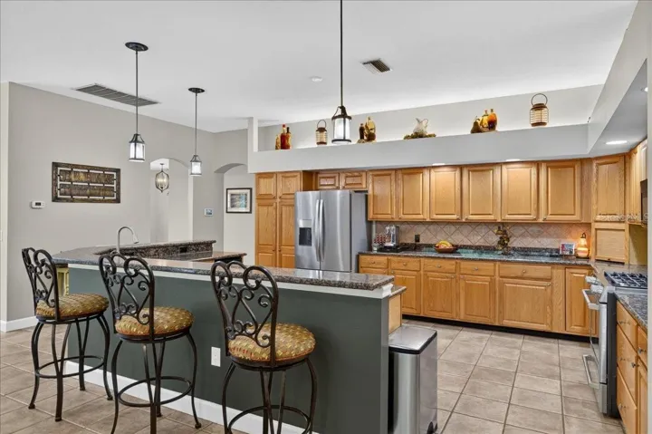 The spacious, well-appointed kitchen features abundant oak cabinetry, granite countertops, stainless steel appliances, a gas range, wine storage and an elevated breakfast bar with seating overlooking and flowing seamlessly into the family room and breakfast nook.