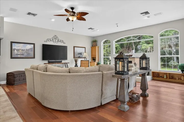 the impressive family room draws in the surrounding scenery through a striking arrangement of arched windows and multiple sets of French doors. Rich cherry wood floors and a gas fireplace bring warmth to this bright, open gathering space.