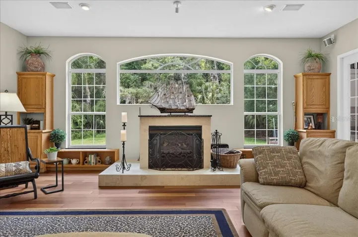 the impressive family room draws in the surrounding scenery through a striking arrangement of arched windows and multiple sets of French doors. Rich cherry wood floors and a gas fireplace bring warmth to this bright, open gathering space.