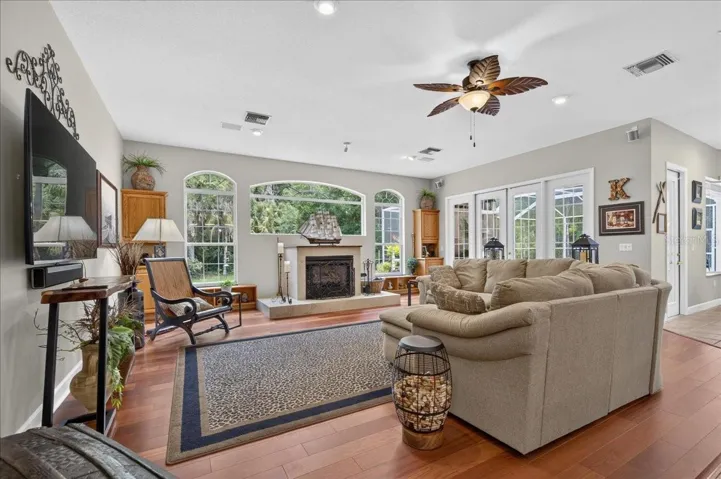 the impressive family room draws in the surrounding scenery through a striking arrangement of arched windows and multiple sets of French doors. Rich cherry wood floors and a gas fireplace bring warmth to this bright, open gathering space.