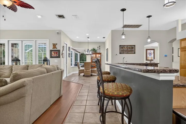 the impressive family room draws in the surrounding scenery through a striking arrangement of arched windows and multiple sets of French doors. Rich cherry wood floors and a gas fireplace bring warmth to this bright, open gathering space.