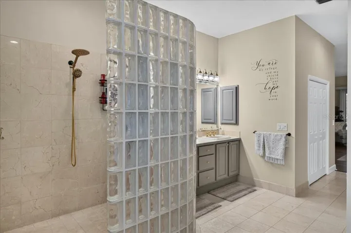 The ensuite bath offers extensive marble finishes, soaking tub, an oversized shower with a curved glass-block wall, double-sink vanity, and a separate water closet with bidet.