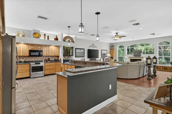 The spacious, well-appointed kitchen features abundant oak cabinetry, granite countertops, stainless steel appliances, a gas range, wine storage and an elevated breakfast bar with seating overlooking and flowing seamlessly into the family room and breakfast nook.
