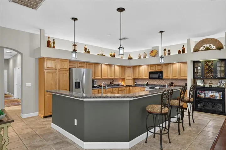 The spacious, well-appointed kitchen features abundant oak cabinetry, granite countertops, stainless steel appliances, a gas range, wine storage and an elevated breakfast bar with seating overlooking and flowing seamlessly into the family room and breakfast nook.