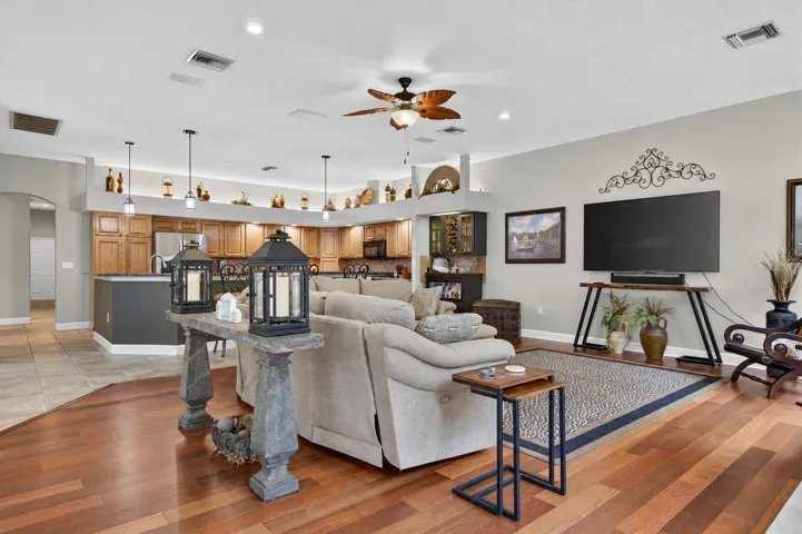 the impressive family room draws in the surrounding scenery through a striking arrangement of arched windows and multiple sets of French doors. Rich cherry wood floors and a gas fireplace bring warmth to this bright, open gathering space.