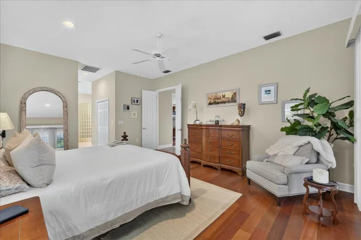The primary bedroom retreat is set apart within the split-bedroom plan and features a transom window and French doors to the lanai and views beyond. Two walk-in closets with built-in organizers provide generous storage