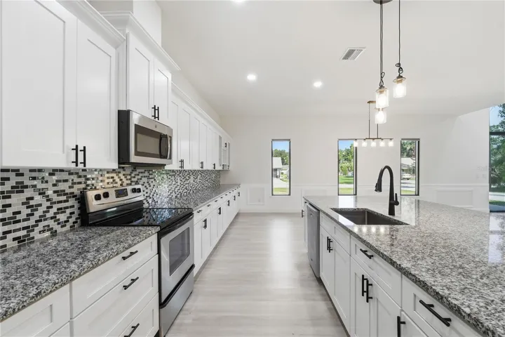 This beautifully appointed kitchen offers an abundance of soft-close cabinetry and drawers, providing generous storage without sacrificing style. The oversized granite island and extensive counter space create the perfect setting for preparing meals, entertaining guests, or enjoying casual family gatherings.
