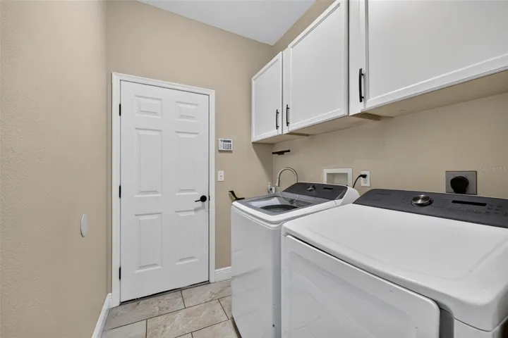 Laundry area with built in cabinets, laundry tub and leads into the 3 car garage