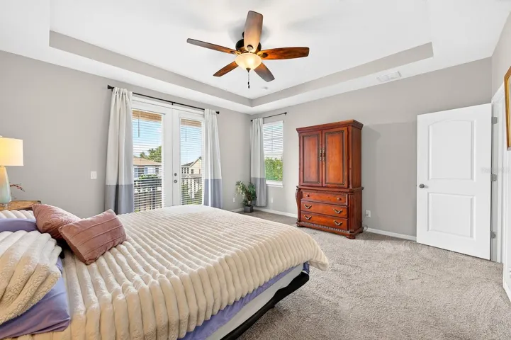 The luxurious Primary Suite is a peaceful retreat featuring an ELEGANT TRAY CEILING and French doors that open to a private balcony.
