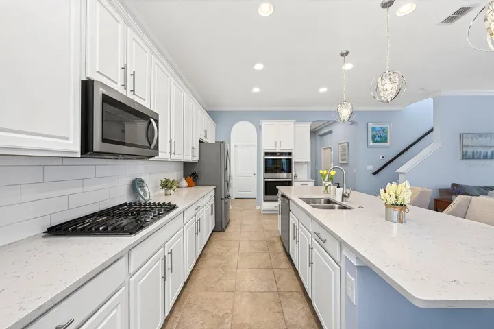 The GOURMET KITCHEN is designed to impress showcasing crisp white cabinetry, stone countertops, a classic subway tile backsplash, stainless steel appliances, a GAS COOKTOP, built-in ovens, a generous closet pantry, an oversized breakfast bar and butler pantry.