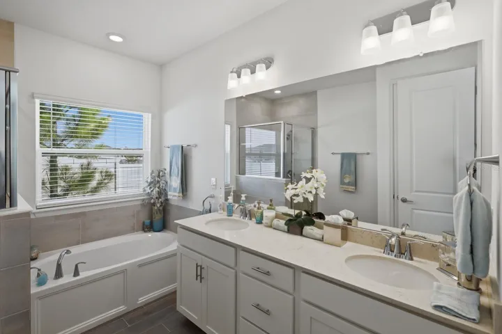 The ensuite primary bathroom has a large soaking tub and separate tiled showed. Featuring the wood plank style tile that is in the main living areas.
