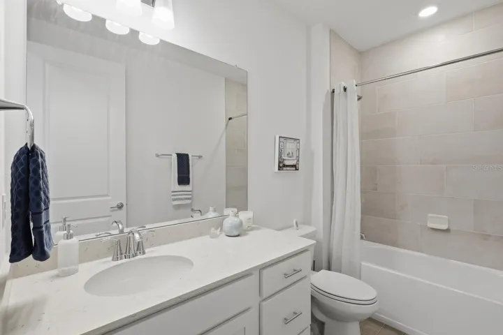 The second bathroom has more beautiful tile, tub/shower combination and quartz countertop.