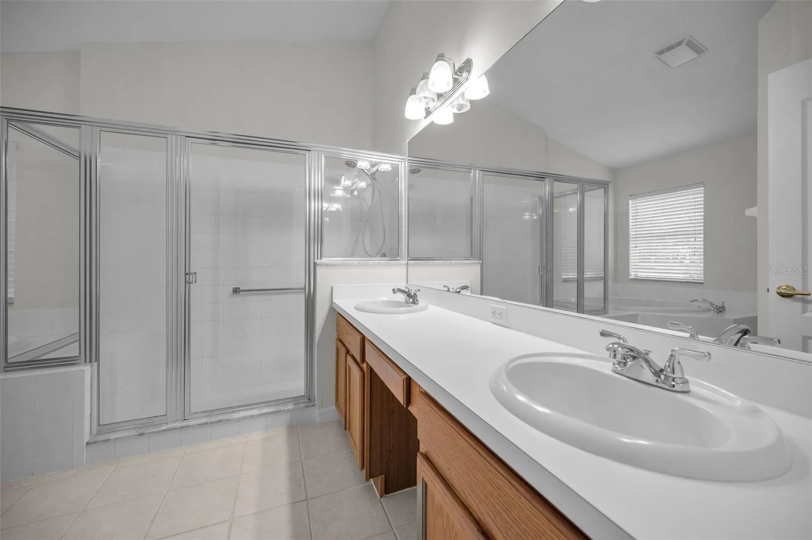 PRIMARY BATHROOM WITH WOOD CABINETS, DUAL SINKS AND LARGE WALK IN SHOWER, IT ALSO BOASTS A LARGE GARDEN TUB.