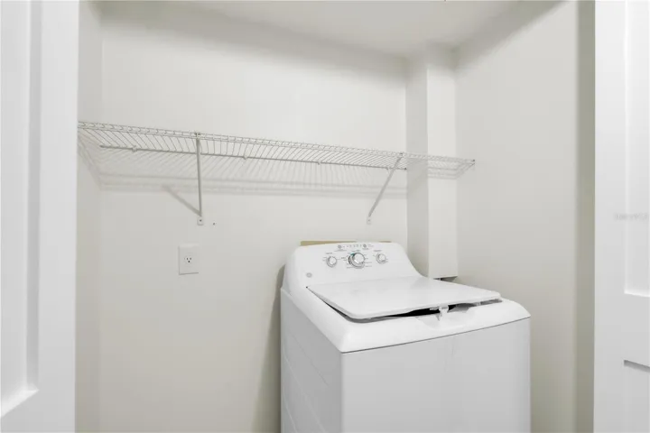 In home laundry with washing machine and storage shelf