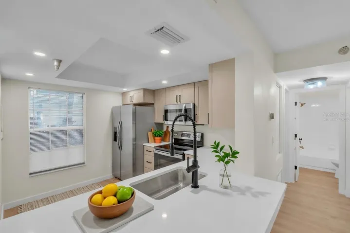 Kitchen with quartz countertops, stainless steel appliances, and an open pass-through to the living area - virtually staged