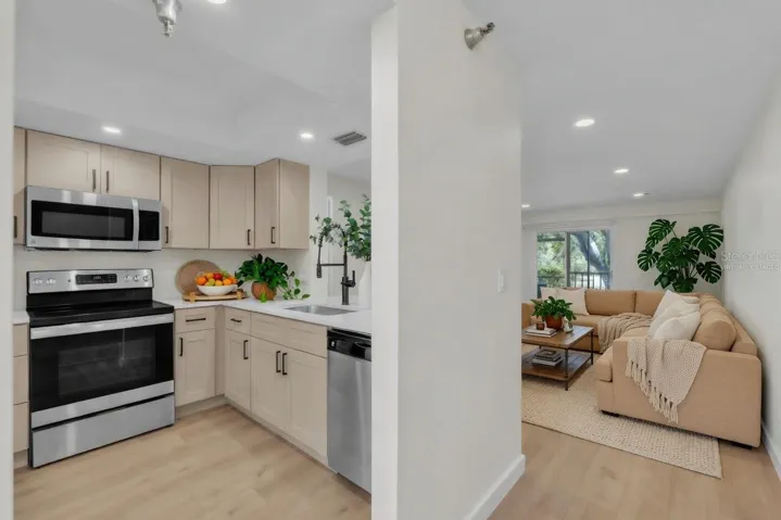 Kitchen with quartz countertops, stainless steel appliances, and an open pass-through to the living area - virtually staged