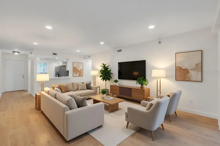 Spacious open-concept living room with luxury vinyl flooring, recessed lighting, and a bright, airy layout - virtually staged