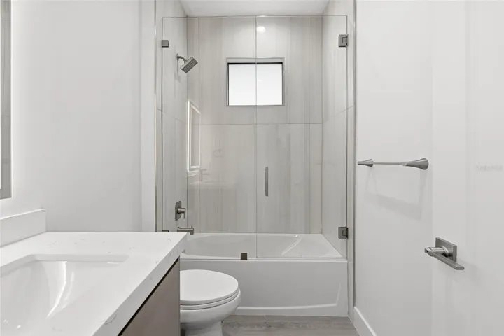 Guest Bathroom with Quartz Vanity and Tub/Shower Combo with Glass Enclosure