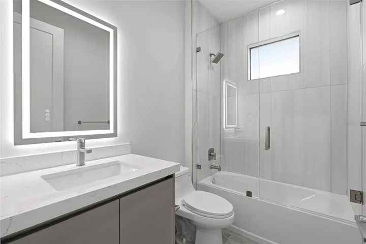 Guest Bathroom with Quartz Vanity and Tub/Shower Combo with Glass Enclosure
