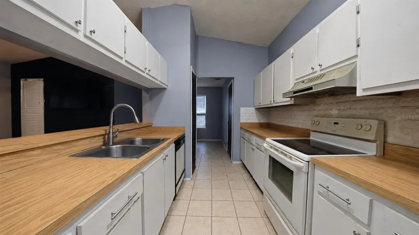 Kitchen with wood countertops and white cabinetry