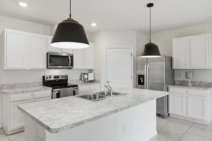 This kitchen features sleek stainless steel appliances, an oversized central island topped with elegant countertops, and an open-concept layout that seamlessly overlooks the dining and living areas, perfect for entertaining.