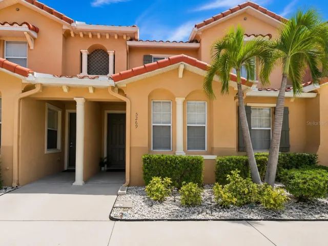 Charming Mediterranean-style townhome for lease in gated Paradise Cay, Kissimmee FL 34746. This 3-bedroom, 3-bath townhouse features a barrel-tile roof, stucco exterior, and lush tropical palm landscaping in a quiet Osceola County community.