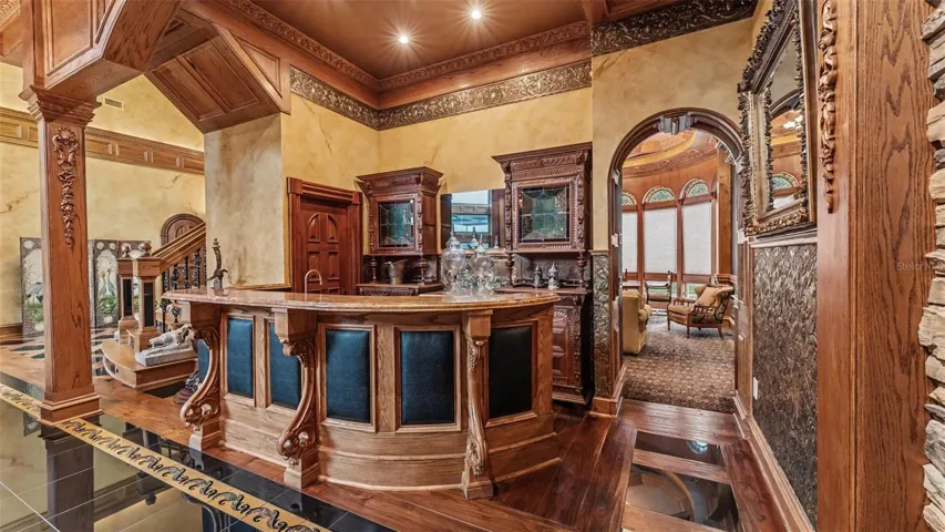 Built from rich, solid Oak,  the back bar features intricate hand carved 19th Century German Renaissance Revival and German Gothic Revival Craftmanship Back Bar Cabinets. The Massive Hand Carved wooden Corbels support the over hanging Polished Marble Bar top with under-mount Copper sink. The Multi-layered wood bas board trim, Fluted Arched Millwork. As you step through the Fluted Archway it creates a seamless transition into the adjacent Study or gaming room.