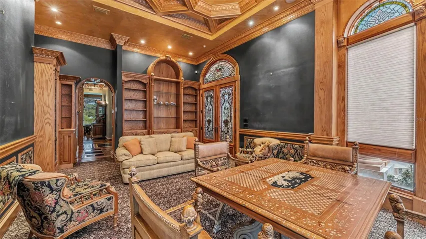 Boardroom/ Library, showing off the Layered Millwork of the coffered ceiling, Leaded Glass door, arched windows and bookshelves. Hand carved table and chairs are so inviting!.