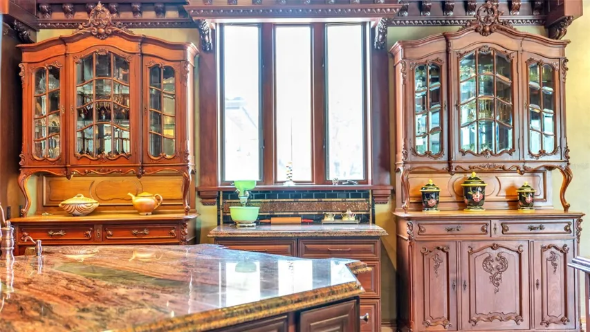 Anchored by Twin Antique Hutches, the kitchen features stately Symmetrical millwork, Exotic Solarious Natural Stone Island. Every slab features dramatic swirling veins, creating a living piece of art across the counters.